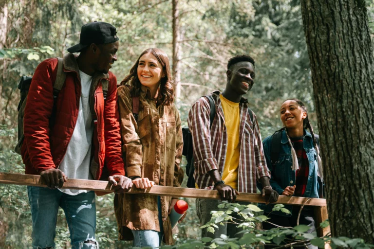Groupe de jeunes souriants ensemble dans une forêt, illustrant l'action collective face à l'éco-anxiété