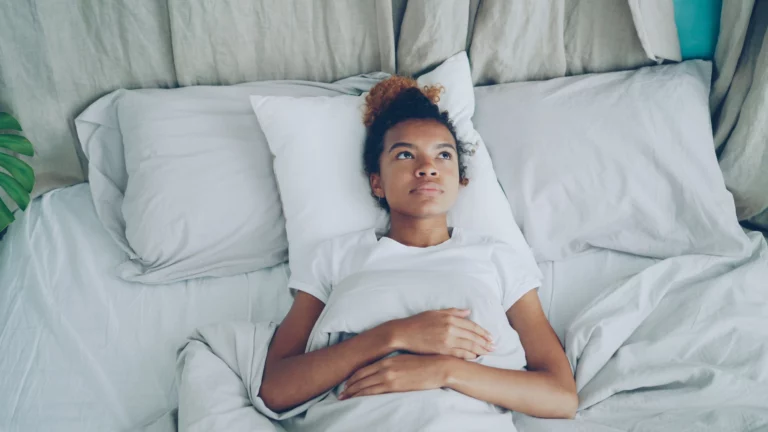 Jeune femme allongée dans son lit les yeux ouverts, incapable de dormir