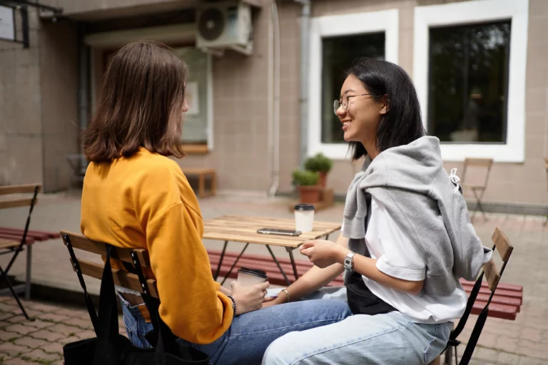 Deux jeunes femmes discutent en terrasse, illustration d'une amitié à sens unique