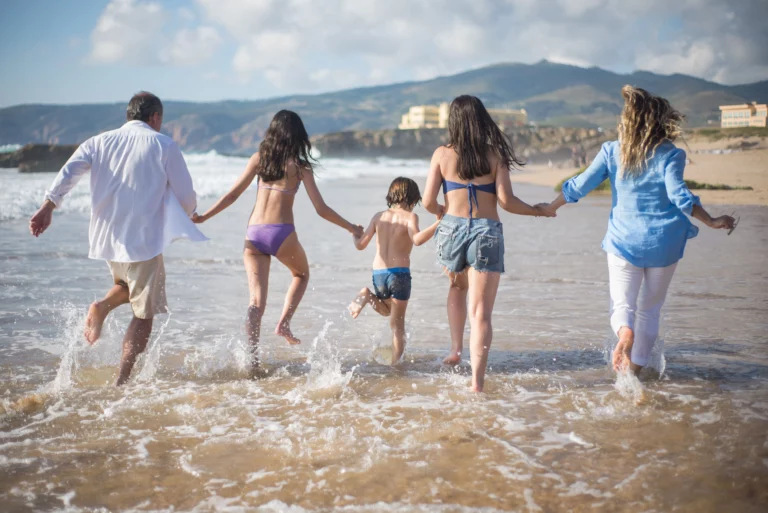 Famille courant main dans la main dans les vagues, les liens familiaux au cœur du sentiment de place